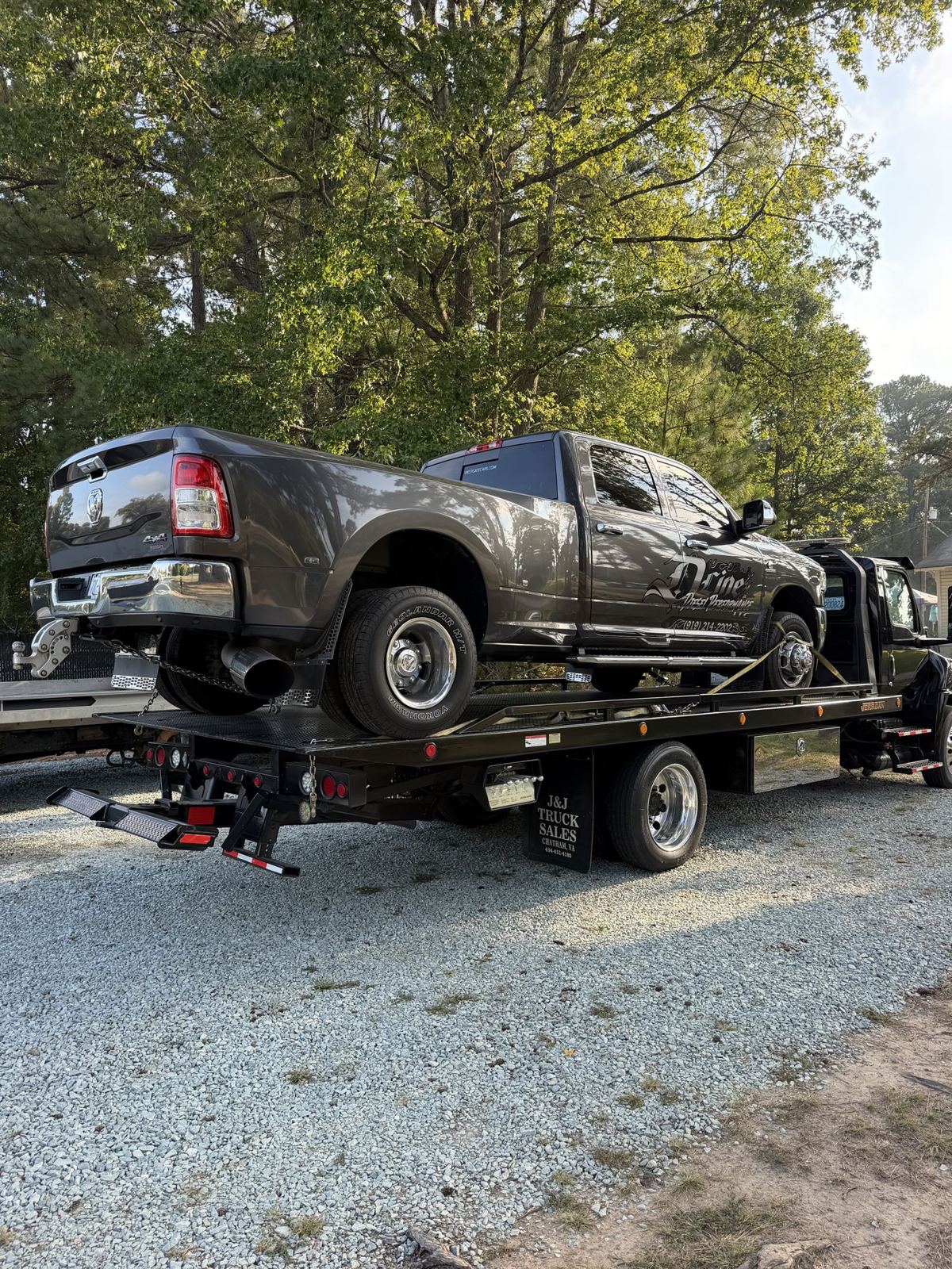 Ram dually pickup strapped down on a 22-ft steel rollback tow truck